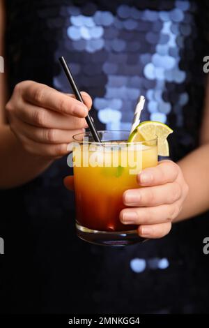 Frau mit einem Glas Tequila Sunrise, Nahaufnahme. Köstlicher alkoholischer Cocktail Stockfoto