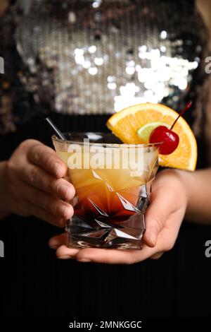 Frau mit einem Glas Tequila Sunrise, Nahaufnahme. Köstlicher alkoholischer Cocktail Stockfoto