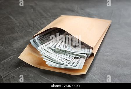 Umschlag mit Dollarscheinen auf grauem Steintisch. Bestechungskonzept Stockfoto