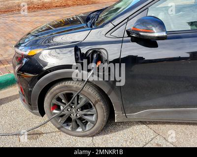 Chevy Bolt EUV, Elektroauto oder Automobil, angeschlossen an eine Straßenladestation zum Aufladen am Straßenrand, in Montgomery Alabama, USA. Stockfoto