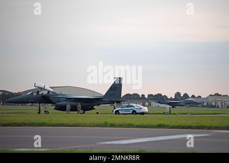 Ein F-15E Strike Eagle-Flugzeug, das dem 366. Fighter Wing, Mountain Home Air Force Base, Idaho, zugewiesen wurde, sitzt auf der Fluglinie, während ein zusätzliches F-15-Flugzeug bei der Royal Air Force Mildenhall, England, am 3. Oktober 2022 landet. Die RAF Mildenhall beherbergt das ganze Jahr über transiente Flugzeuge, was es der Expeditionary Air Force ermöglicht, in einem Augenblick rund um den Globus zu fliegen. Stockfoto