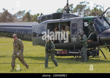 Das Batteriekommando und die Mitarbeiter der 1-265th Air Defense Artillery (ADA) lassen einen UH-1 Irokesen absteigen, der von Mitgliedern des Charlotte Sheriff’s Department zurückgeflogen wurde, um eine Vermessung des Charlotte County durchzuführen und das Ausmaß der Zerstörung durch Hurrikan Ian zu bewerten. Port Charlotte, Florida. Oktober 2022. Mehr als 6.000 Soldaten wurden als Reaktion auf die Naturkatastrophe aktiviert und sowohl militärische als auch zivile Unterstützung von außerstaatlichen Standorten. 22DoDHurricane, AlwaysThereAlwaysReady, HurricaneIan, Nationalgarde, Stockfoto
