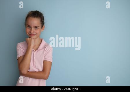 Kleines emotionales Teenager-Mädchen im rosa Hemd, 11, 12 Jahre alt, auf isoliertem blauem Hintergrund. Studioporträt für Kinder. Stockfoto