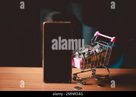 Handymodell neben Münzkorb.Online-Shopping-Konzept. Stockfoto