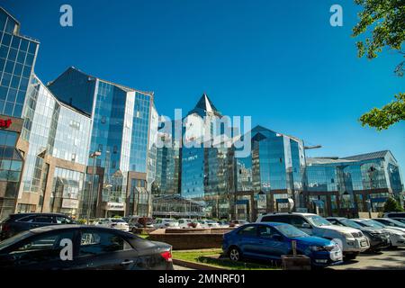 Parkplätze mit Autos vor dem Büro von Nurly Tau und dem Business Center in Almaty Stockfoto