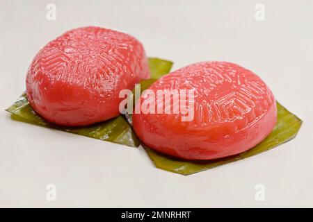 Gedünstete rote Schildkrötenkuchen oder „Ang Ku Kueh“, ein traditionelles chinesisches Gebäck mit glutartiger Reismehlhaut auf Bananenblättern Stockfoto