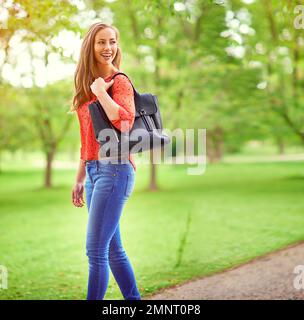 Auf einem gemütlichen Spaziergang durch den Park. Eine junge Frau, die in einem Park spaziert. Stockfoto