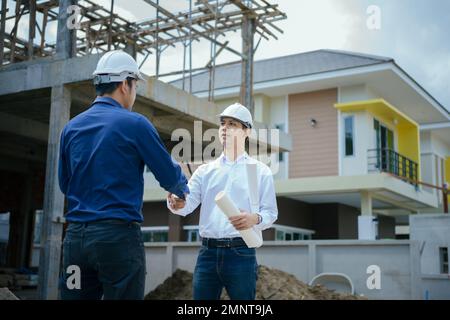 Ingenieure geben sich auf der Baustelle die Hand. Arbeiter und Bauleiter schütteln sich die Hände, während sie für Teamarbeit arbeiten. Stockfoto