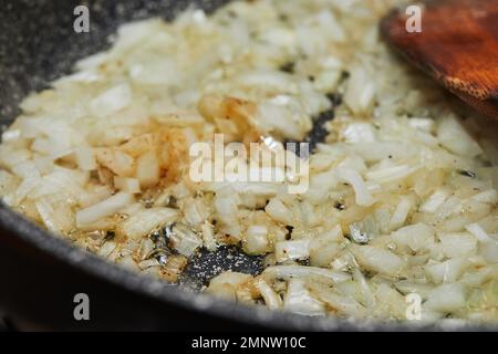 Zwiebeln werden in einer Bratpfanne frittiert und selektiv fokussiert Stockfoto