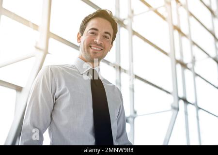 Erfolg bringt mir immer ein Lächeln ins Gesicht. Verkürztes Porträt eines Geschäftsmanns, der in der Lobby steht. Stockfoto