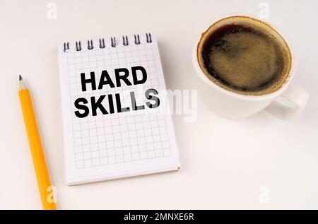 Geschäftskonzept. Auf einer weißen Oberfläche, einer Tasse Kaffee, einem Bleistift und einem Notizblock mit der Aufschrift "Hard Skills" Stockfoto