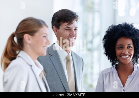 Unternehmensvielfalt. Ein glücklicher Geschäftsmann steht neben seinen beiden weiblichen Kollegen. Stockfoto