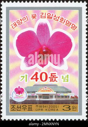 Nordkoreanische Briefmarke aus dem Jahr 2005 zum 40. Jahrestag der Namensgebung der Kimilsungia-Orchidee mit rosa Blume und Halle. Stockfoto