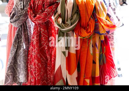 Schals und Scheichen hängen in einem Laden zum Verkauf auf dem Straßenmarkt Stockfoto