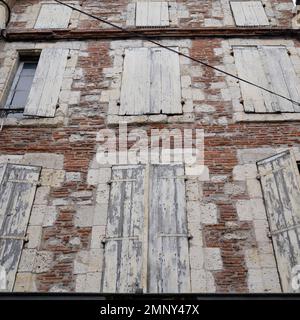 Alte verlassene Haus weiße Holzläden, alt in Ziegelmauern Stockfoto