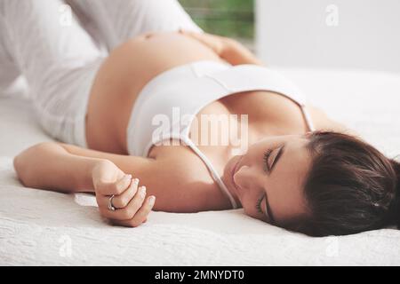 Schwangerschaftspause. Eine schwangere Frau schläft zu Hause auf ihrem Bett. Stockfoto