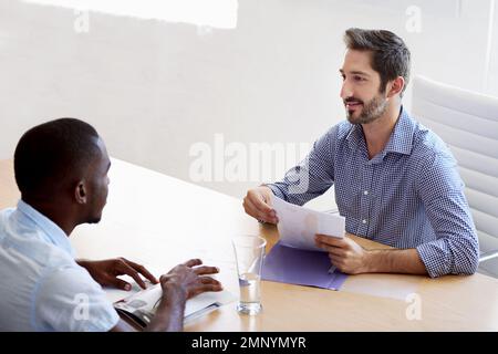 Vorstellungsgespräch läuft... ein Geschäftsmann führt ein Vorstellungsgespräch mit einem Bewerber in einem Büro. Stockfoto