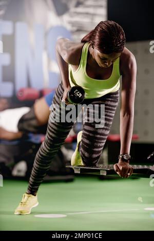Streben nach Stärke. Eine junge Frau, die im Fitnessstudio Gewichte hebt. Stockfoto
