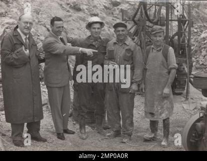 Vintage-Moment / Vintage-lustiger Moment / Vintage-Foto / Power of the Moment / magische Momente / Vintage-lustiger Moment außerhalb der Sandmine. Die Bergleute stehen neben dem Management und lachen über etwas im 1950er Stockfoto