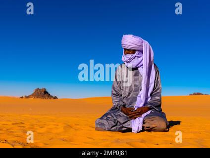 Tuareg sitzt in der Sahara-Wüste, Nordafrika, Erg Admer, Algerien Stockfoto