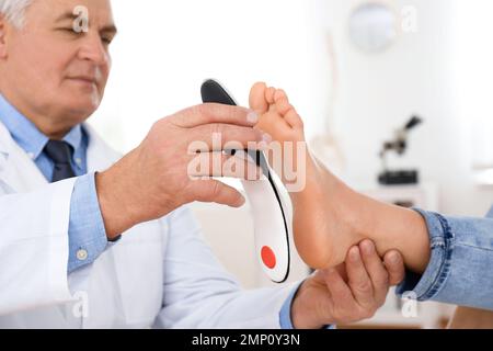 Die Einlegesohle des männlichen Orthopäden am Fuss des Patienten in der Klinik Stockfoto