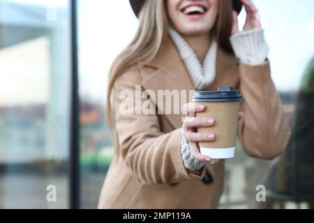 Junge Frau mit einer Tasse Kaffee auf der Straße der Stadt am Morgen, konzentrier dich auf die Hand Stockfoto