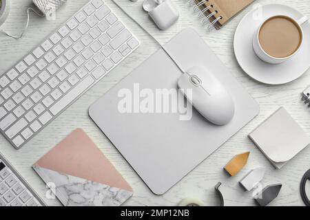 Flache Verlegung mit kabelgebundener Computermaus, Tastatur und Schreibwaren auf weißem Holztisch Stockfoto