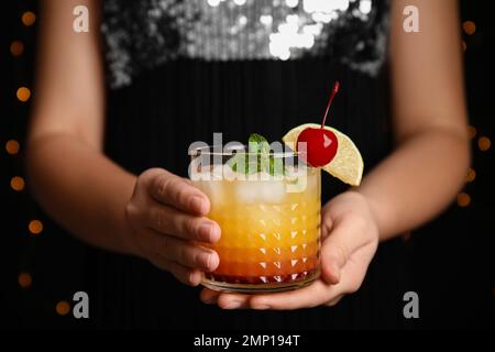Frau mit einem Glas Tequila Sunrise, Nahaufnahme. Köstlicher alkoholischer Cocktail Stockfoto