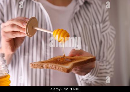 Eine Frau, die Honig auf getoastetes Brot schüttet Stockfoto