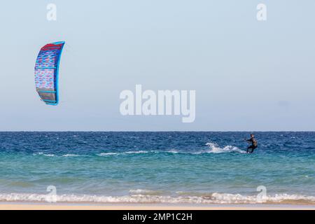 Kitesurfer rutschte auf dem Wasser, getragen von seinem blauen Drachen. Sotavento Beach, Furteventura, Kanarische Inseln. Stockfoto