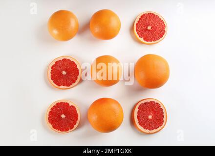 Geschnittene und ganze reife Grapefruits auf weißem Hintergrund, flach liegend Stockfoto