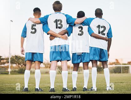 Fußball, Team und Umarmung stehen mit dem Rücken auf dem Platz in Partnerschaft, Vertrauen oder bereit für ein Sportspiel oder ein Spiel. Sportler, die sich in Teamarbeit umarmen Stockfoto