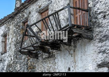 Verlassenes altes Haus mit Holzfenstern und einem komplett zerstörten Balkon auf Steinmauern Stockfoto