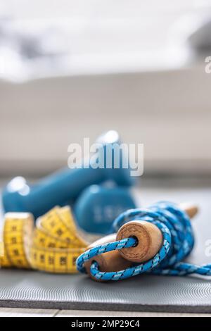 Springseil, Kurzhanteln und Maßband auf der Matte zu Hause im Wohnzimmer. Konzept einer gesunden Lebensweise. Stockfoto