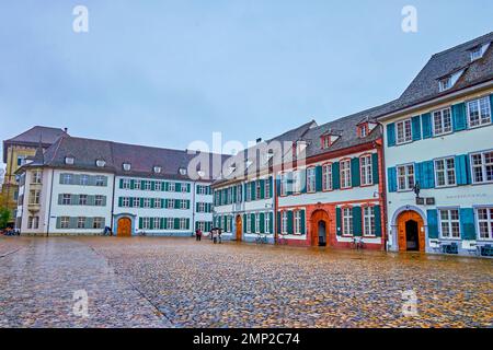 BASEL, SCHWEIZ - 1. APRIL 2022: Malerische traditionelle Häuser auf dem Platz der Münsterkirche, am 1. April in Basel, Schweiz Stockfoto