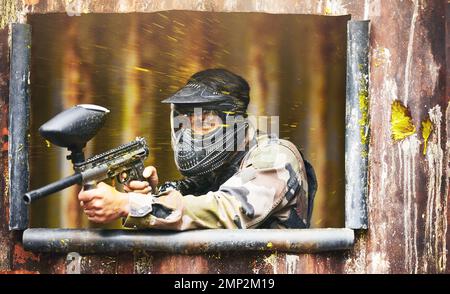 Paintball, Pistole und Tarnung mit einem Sportler, der ein Militärspiel spielt, um Spaß zu haben oder im Freien zu trainieren. Krieg, Soldat und Ziel mit einem männlichen Athleten Stockfoto