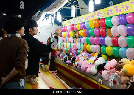 Die Teilnehmer spielen ein Ballon-Dartspiel während der Republik Korea 19. und des Kulturfestivals der Vereinigten Staaten, vor dem Luftwaffenstützpunkt Osan, Republik Korea, am 8. Oktober 2022. Nach Eröffnungsanmerkungen und Vorstellungen gönnten sich die Teilnehmer Street Food, spielten Spiele und kauften lokale Waren von verschiedenen Anbietern. Stockfoto