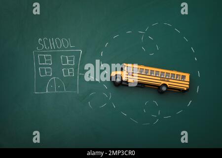 Gelber Bus und Zeichnung der Schule auf Tafel, Draufsicht. Transport für Studenten Stockfoto