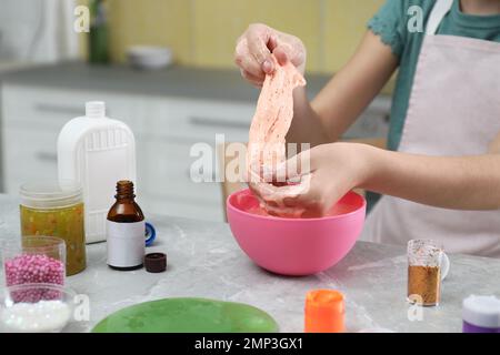 Kleines Mädchen, das Heimwerker-Schleim-Spielzeug am Tisch in der Küche knete, Nahaufnahme Stockfoto