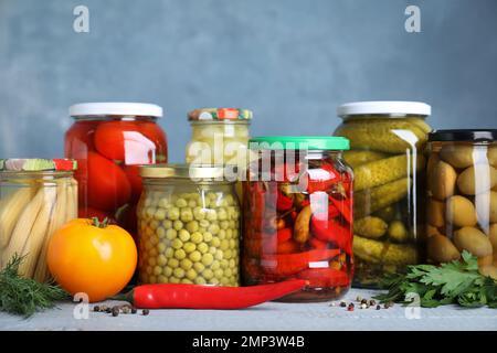 Glasgefäße mit verschiedenen eingelegten Gemüsesorten auf dem Tisch Stockfoto