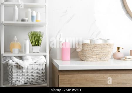 Korb aus Korb mit Toilettenpapierrollen auf der Ablagefläche im Badezimmer Stockfoto