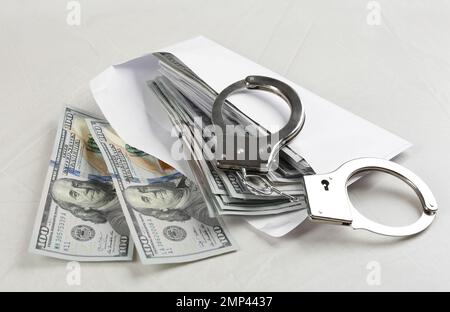 Dollarscheine und Handschellen auf einem Tisch aus hellgrauem Stein. Bestechungskonzept Stockfoto
