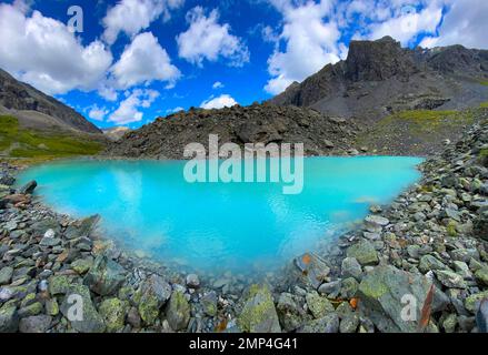 Panorama Bergsee ruhiges Türkis mit klarem Wasser Karakabak in den steinernen Bergen von Altai unter den gedämpften Wolken während des Tages. Stockfoto