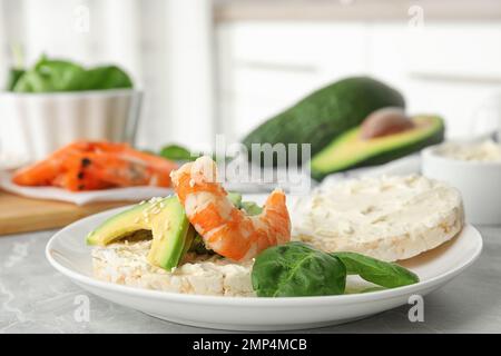 Gepuppter Reiskuchen mit Garnelen und Avocado auf grauem Marmortisch im Innenbereich Stockfoto