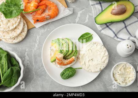 Gepuppter Reiskuchen mit Garnelen und Avocado, serviert auf einem grauen Marmortisch, flach liegend Stockfoto