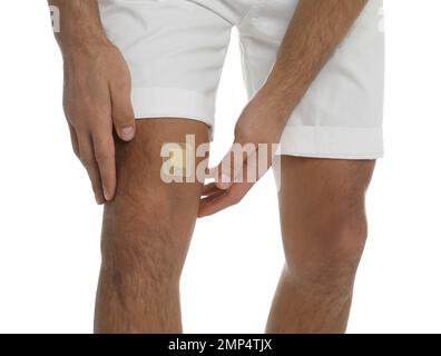 Mann mit Knieputz auf dem Knie vor weißem Hintergrund, Nahaufnahme Stockfoto