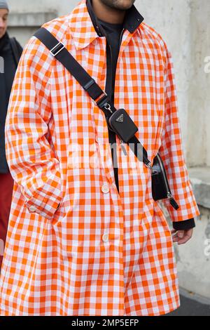 MAILAND, ITALIEN - 15. JANUAR 2023: Mann mit weiß-orangefarbenem Trenchcoat vor der Prada-Modenschau, Mailand Fashion Week Street Style Stockfoto