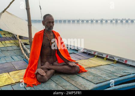 Sadhu mit rotem Schal auf einer Bootsfahrt auf dem Ganges bei Sonnenaufgang, Allahabad Kumbh Mela, der weltweit größte religiöse Versammlung, Uttar Pradesh, Indien Stockfoto