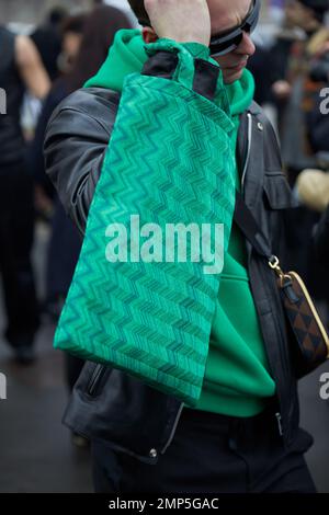 MAILAND, ITALIEN - 15. JANUAR 2023: Mann mit grüner Tasche und Kapuzenpullover vor der Prada-Modenschau, Mailand Fashion Week Street Style Stockfoto