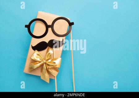 Flacher Blick auf das vollgepackte Geschenk des Vaters mit Schnurrbart und Brille auf blauem Hintergrund, viel Platz für Kopien. Lustiges Grußkartenmodell. Stockfoto